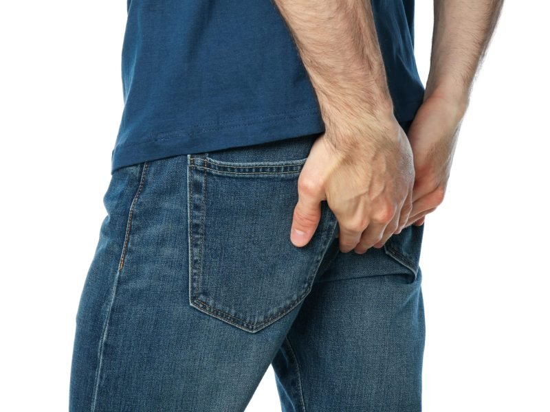 Man holding his butt, isolated on white background